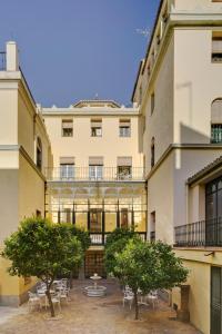 un patio con sillas y árboles frente a un edificio en LoopINN Granada, en Granada