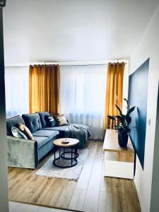 een woonkamer met een blauwe bank en een tafel bij Apartament Króla in Sandomierz