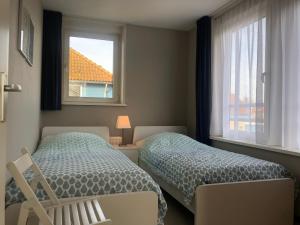 a bedroom with two beds and a window at Maxime 209 - Kustpark Village Scaldia in Hoofdplaat