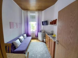a small living room with a purple couch and a window at ELENA flat Lavendel Duisburg Zentrum in Duisburg