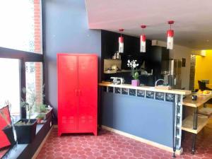 Loft atypique 192m2, terrasse, aux portes de Lille في روبيه: خزانة حمراء في مطبخ مع منضدة حمراء