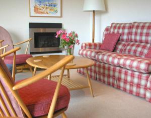 a living room with a couch and a table with flowers on it at Rosevallen in Polzeath +1 photo