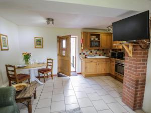 a kitchen with a table and a tv on the wall at Bluebell Cottage Farm Stay in Leominster