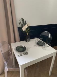 a white table with two plates and wine glasses on it at La Suite Dandy - Beau T2 -Terrasse, Parking gratuit, Climatisation in Bagnères-de-Bigorre