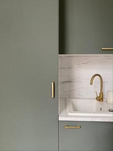 a bathroom with a sink and a gold faucet at La Suite Dandy - Beau T2 -Terrasse, Parking gratuit, Climatisation in Bagnères-de-Bigorre
