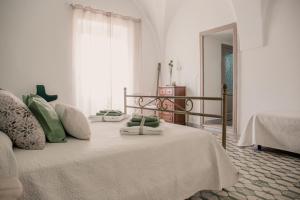 1 dormitorio con 1 cama con manta blanca y ventana en Maison Montpellier, en Ceglie Messapica