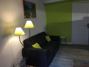 a living room with a black couch and two lamps at appartement à la montagne in Eaux-Bonnes