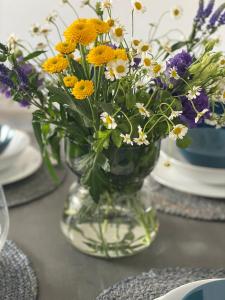 a vase filled with yellow and white flowers on a table at Apartment Gradus in Dunajská Streda