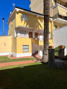プラーイア・ア・マーレにあるL'appartamentoの庭のヤシの木がある黄色い建物