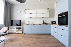 a kitchen with white cabinets and a tv at INA Rent - Nadmorski Dwór in Gdańsk