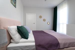 a bedroom with a bed with green and purple pillows at INA Rent - Nadmorski Dwór in Gdańsk