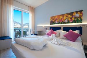 una camera da letto con un grande letto bianco con cuscini rosa di Hotel Firenze 3 Stelle Superior a Brenzone sul Garda