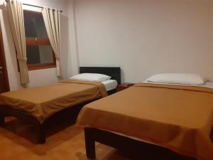 2 Betten in einem kleinen Zimmer mit Fenster in der Unterkunft Griya Bun Sari in Sukawati