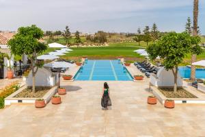 a woman standing in front of a pool at a resort at Address Marassi Golf Resort in El Alamein