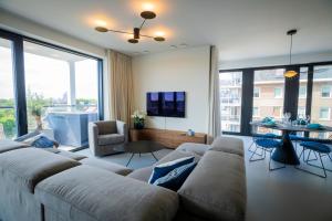 uma sala de estar com um sofá grande e uma mesa em Rots in de Branding Luxurious 2 bedroom apartment in the dunes with sea sight em Cadzand
