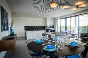 a dining room and living room with a table and chairs at Rots in de Branding Luxurious 2 bedroom apartment in the dunes with sea sight in Cadzand