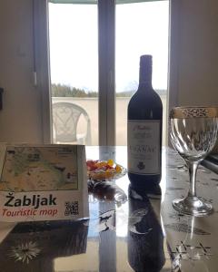 a bottle of wine sitting on a table next to a glass at Apartment Durmitor fairy in Žabljak