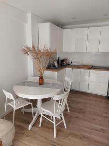 a white kitchen with a white table and chairs at Preilos39 in Preila