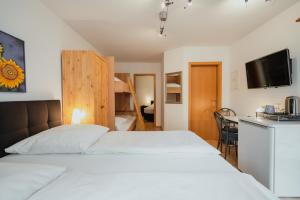 Schlafzimmer mit einem weißen Bett und einem TV in der Unterkunft Park Hotel & Gästehaus Rust in Rust