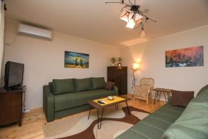 uma sala de estar com um sofá verde e uma mesa em Weekendaya em Kladovo