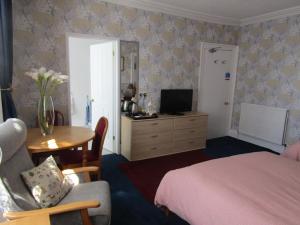 a bedroom with a bed and a table and a tv at Athollbank Guest House in Dundee