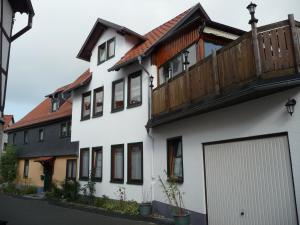 Casa blanca con balcón de madera en la parte superior. en Haus Saskia, en Wutha-Farnroda