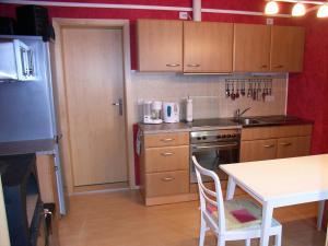 a kitchen with wooden cabinets and a white table and a table and a tablektop at Haus Saskia in Wutha-Farnroda