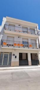 ein weißes Gebäude mit Balkonen und orangefarbenen Stühlen darauf in der Unterkunft Controvento in Porto Cesareo
