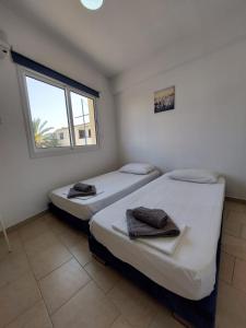 two beds in a room with a window at Downtown Agia Napa in Ayia Napa