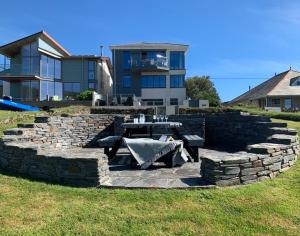 Un muro de contención de piedra con una mesa de picnic frente a una casa. en Egloskerry, en Wadebridge