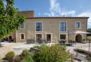 - une vue extérieure sur une maison en pierre dotée de tables et de chaises dans l'établissement Domaine de Montine Chambres de Charme, à Grignan