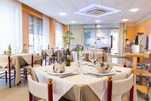 uma sala de jantar com mesas e cadeiras com toalhas de mesa brancas em XXV APRILE Casa per Ferie em Albenga