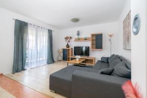 ein Wohnzimmer mit einem grauen Sofa und einem TV in der Unterkunft Modern apartment with private pool in Bibinje