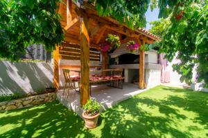 a wooden pergola with a table and chairs in a yard at Modern apartment with private pool in Bibinje