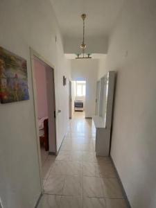 un couloir avec une chambre dotée de murs blancs et de carrelage. dans l'établissement Vollga Promenade Lovely 2 bedroom Apartment, à Durrës