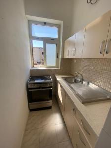 Il comprend une cuisine équipée d'une cuisinière et d'un évier. dans l'établissement Vollga Promenade Lovely 2 bedroom Apartment, à Durrës