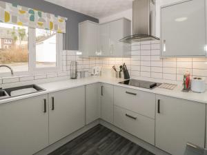 a kitchen with white cabinets and a sink and a window at The Annexe in Menai Bridge +9 photos