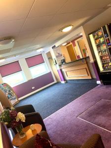um quarto com paredes roxas e uma mesa e cadeiras em Purple Roomz Preston South em Preston