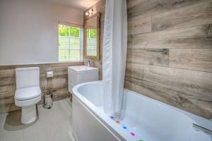 a bathroom with a toilet and a tub and a sink at The Coach House in Abersoch +23 photos