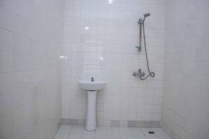 a white tiled bathroom with a sink and a shower at Super villa avec garage véhicule à 2 mn de la mer in Lomé