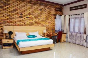 - une chambre avec un lit et un mur en briques dans l'établissement SamWeb Bed and Breakfast, à Kampala