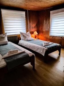 two beds in a room with wooden walls and windows at Apartments "FERMAN" Visoko in Visoko +11 photos