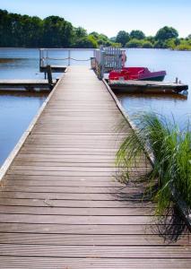 a wooden dock with a boat on the water at Seeblick in Mühbrook