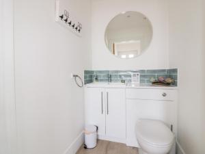 a white bathroom with a toilet and a mirror at Gwel Nans in St. Agnes +18 photos