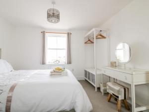 a white bedroom with a bed and a desk at Gwel Nans in St. Agnes