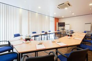 a conference room with tables and chairs and a screen at Hotel Mondial in Langenfeld