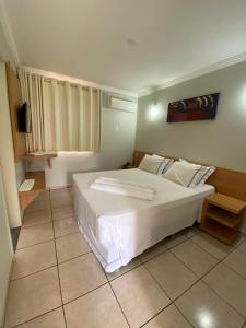 1 dormitorio con 1 cama blanca grande en una habitación en diRoma Internacional Resort com Piscinas 24h e um dia no Acqua Parque e Splash, en Caldas Novas
