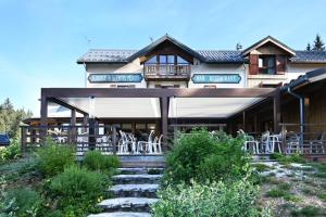 - un grand bâtiment avec des chaises blanches devant dans l'établissement Auberge De La Croix Perrin, à Lans-en-Vercors