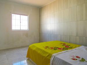 a bedroom with a bed with a yellow blanket at Casa com Piscina e Churrasqueira em Vera Cruz BA in Barra Grande