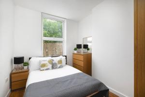 ein weißes Schlafzimmer mit einem Bett und einem Fenster in der Unterkunft Skyvillion - Lovely 2-Bed Central London Apartment in London